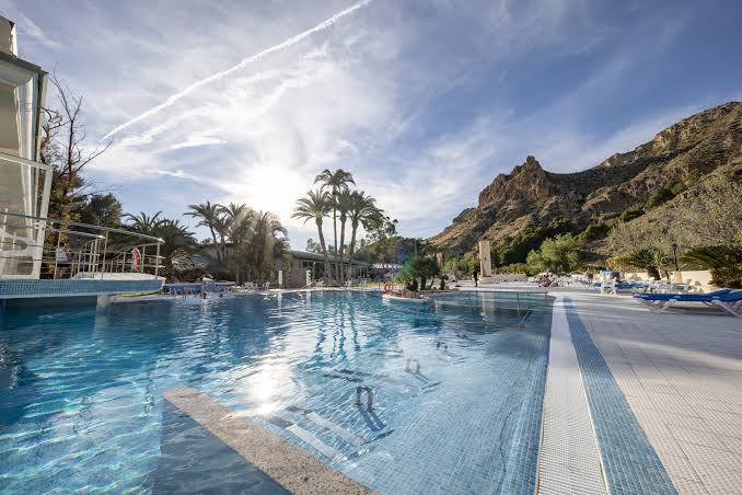 Thermal pool at Balneario de Archena with palm trees and mountains